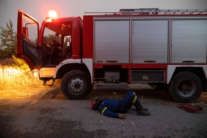 A firefighter rests at dawn as a wildfire burns near the village of Asklipieio, on the island of Rhodes, Greece, on July 24, 2023.