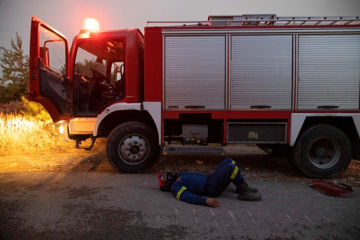 A firefighter rests at dawn as a wildfire burns near the village of Asklipieio, on the island of Rhodes, Greece, on July 24, 2023. 