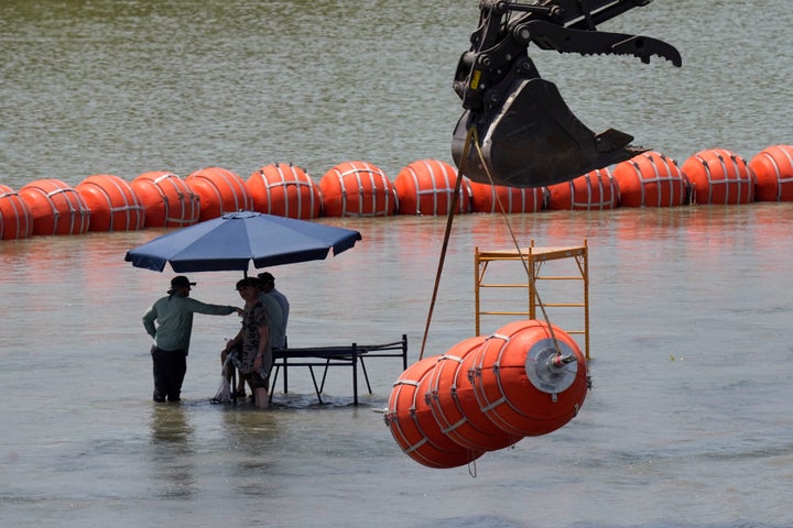 Workers take a break from deploying large buoys to be used as a border barrier along the banks of the Rio Grande in Eagle Pass, Texas, on July 12.