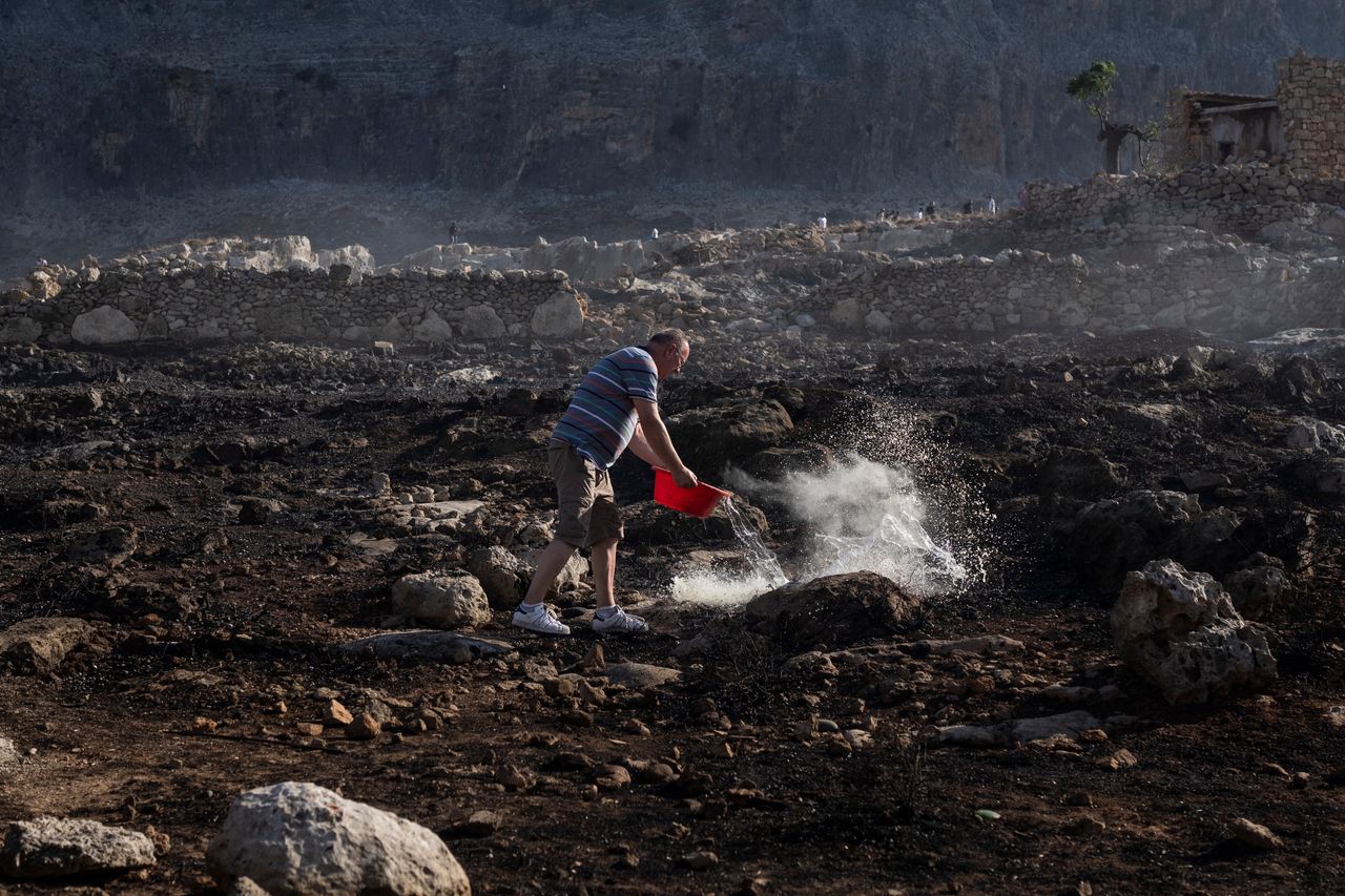 Ανδρας προσπαθεί να σβήσει μια μικροεστία φωτιάς με νερό που μετέφερε σε μια λεκάνη