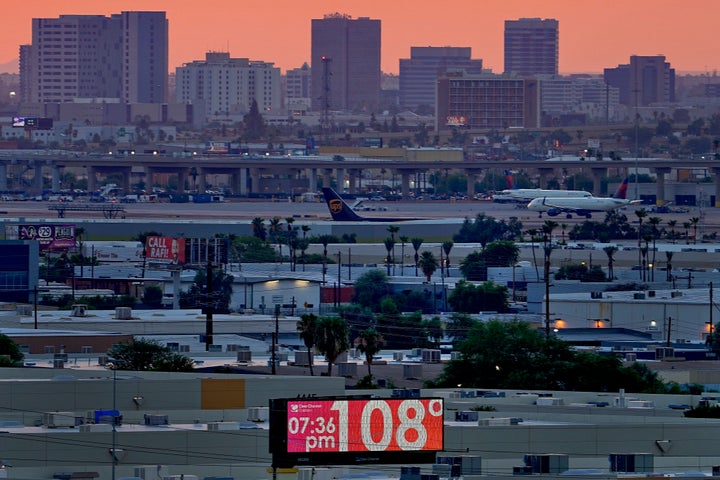 A sign displays an unofficial temperature as jets taxi at Sky Harbor International Airport at dusk on Jul. 12, 2023, in Phoenix, Arizona.