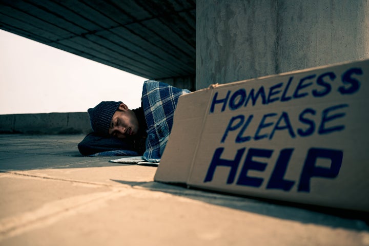 Homeless man slept on a piece of cardboard with an old blanket.