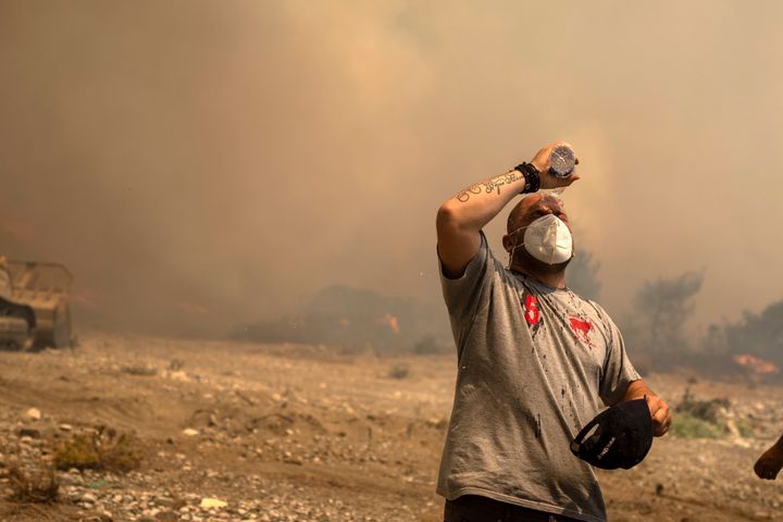 A volunteer cools himself during a wildfire in Vati village, on the Aegean Sea island of Rhodes, southeastern Greece, on July 25, 2023.