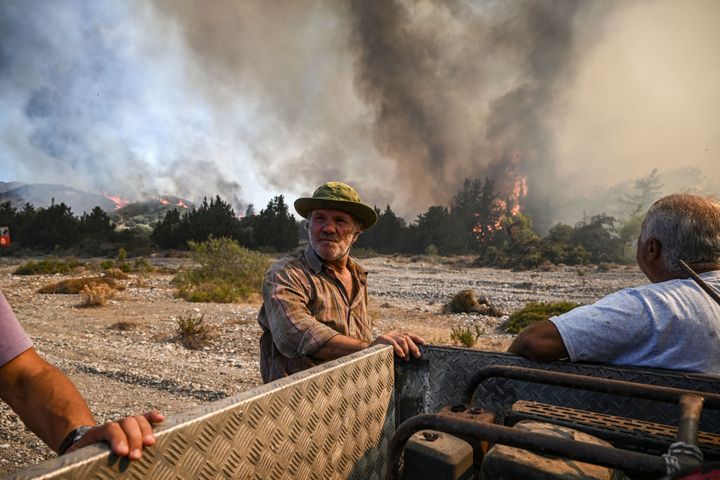 Men stand by their pick-up truck as they watch wildfires close to the village of Vati on the Greek island of Rhodes on July 25, 2023. 
