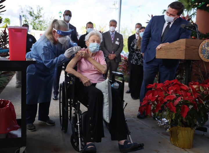 Florida Gov. Ron DeSantis (R) looks on as Vera Leip, 88, receives a Pfizer-BioNtech COVID-19 vaccine at the John Knox Village Continuing Care Retirement Community on Dec. 16, 2020, in Pompano Beach, Florida. The facility, one of the first in the country to do so, vaccinated approximately 170 people.