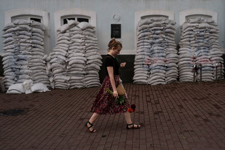 Μια γυναίκα με λουλούδια περπατάει μπροστά από ένα κτίριο οχυρωμένο με σακιά άμμου στη γειτονιά Podil του Κιέβου, Ουκρανία, Πέμπτη 27 Ιουλίου 2023.