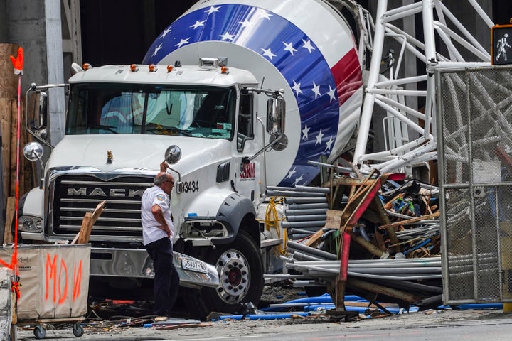 Part of the extension arm from a hi-rise construction crane lies crashed against a cement truck on Thursday. The crane caught fire on Wednesday, losing the long arm which smashed into a nearby building as it plummeted to the street.