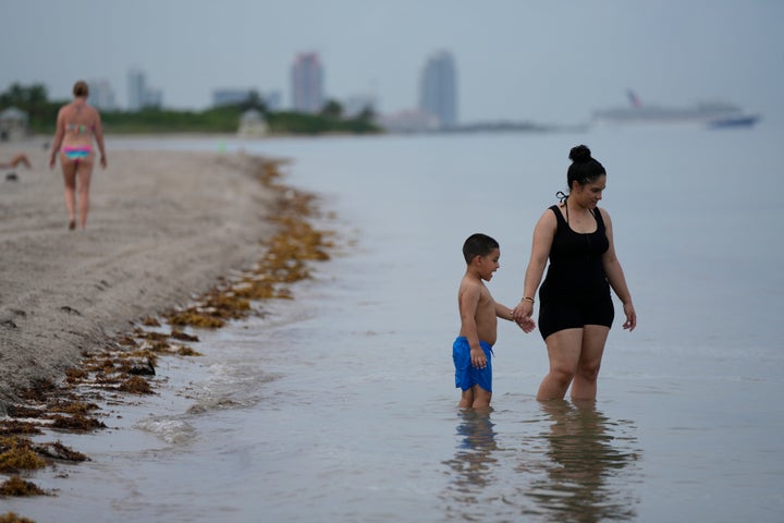 Beachgoers wade in the ocean at Crandon Park, Friday, July 28, 2023, in Key Biscayne, Florida.