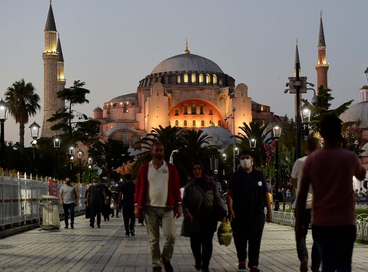 People walk backdropped by the Byzantine-era Hagia Sophia, in the historic Sultanahmet district of Istanbul, Friday, July 24, 2020. Worshipers held the first Muslim prayers in 86 years inside the Istanbul landmark that served as one of Christendom's most significant cathedrals, a mosque and a museum before its conversion back into a Muslim place of worship. The conversion of the edifice, has led to an international outcry. (AP Photo/Yasin Akgul)
