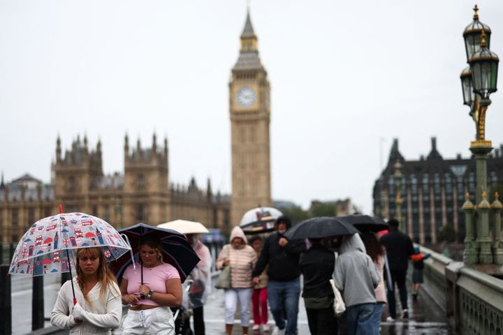 Umbrellas up as people walks across Westminster Bridge, London.