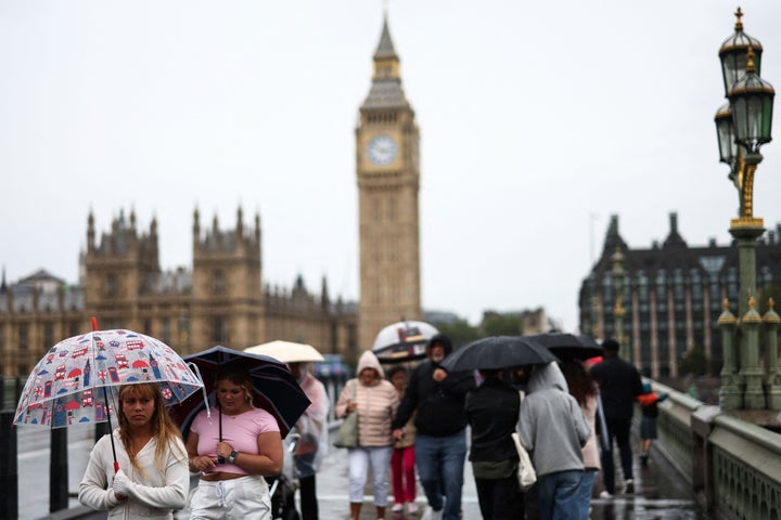 Umbrellas up as people walks across Westminster Bridge, London.