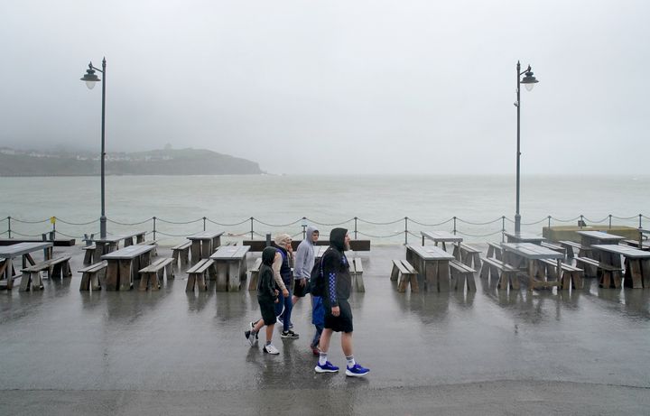 A family walks amongst empty picnic tables during bad weather in Folkestone, Kent.