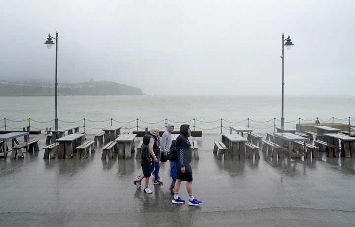 A family walks amongst empty picnic tables during bad weather in Folkestone, Kent.