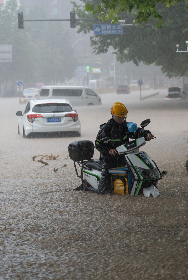 A deliveryman riding a motorbike is trapped in flood waters in Mengtougou district on July 31, 2023 in Beijing.