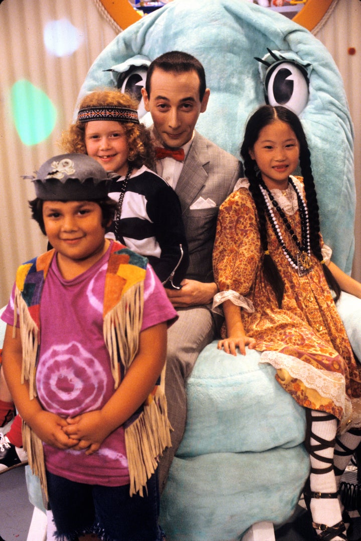 Natasha Lyonne senta no colo de Paul Reubens durante uma promo ainda para “Pee-wee's Playhouse” em 1986.