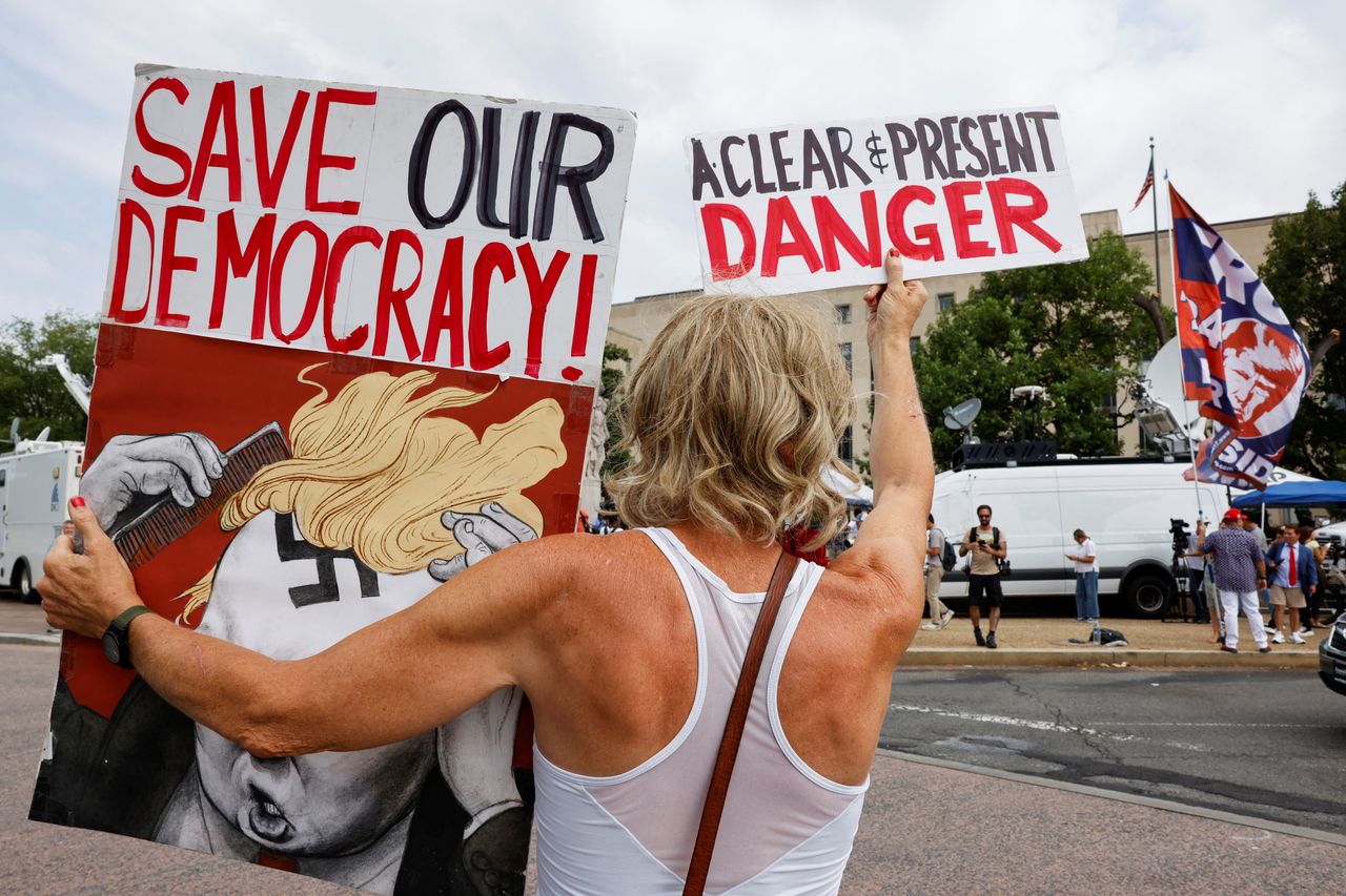 Nicky Sundt, a D.C. resident, holds up a sign on the day Trump is arraigned in federal court.