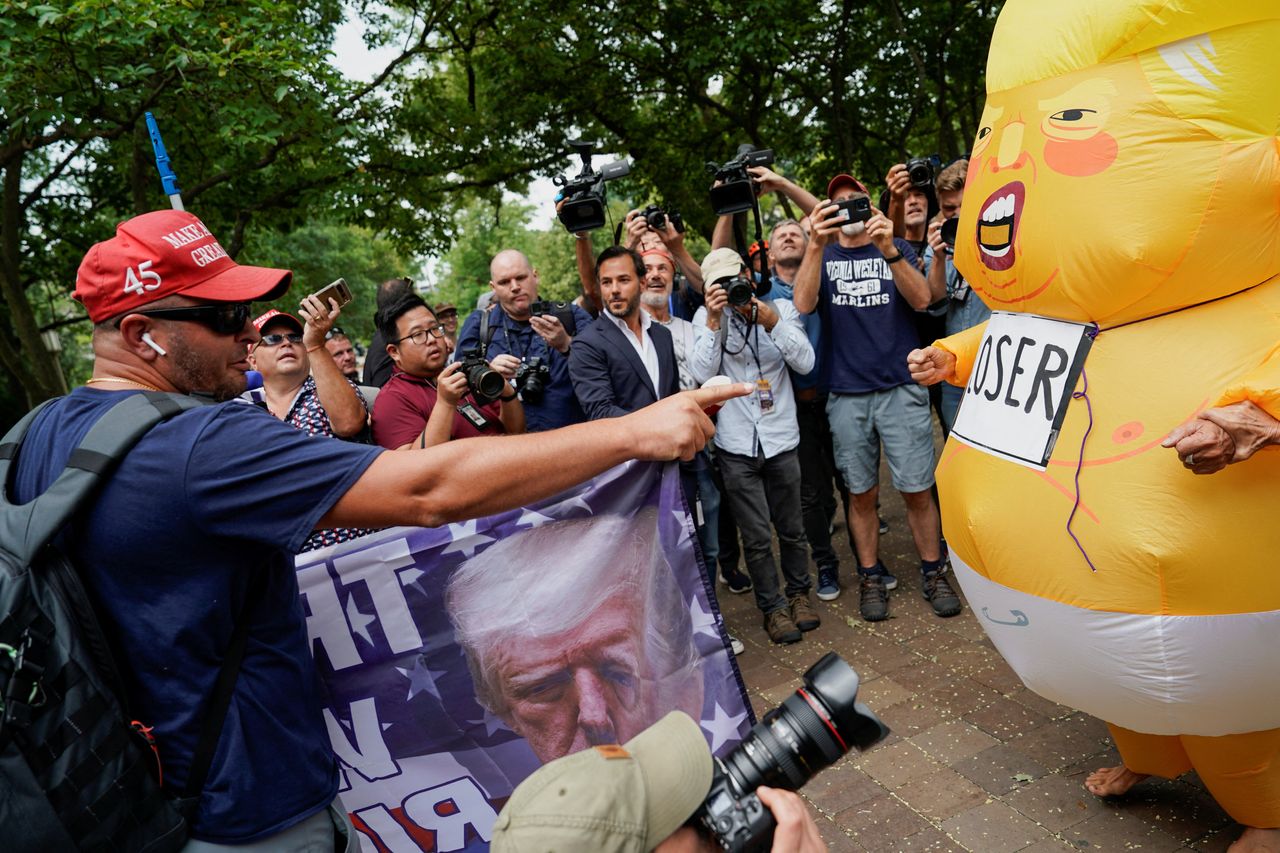 A demonstrator in a MAGA hat faces off with a demonstrator in a Baby Trump costume.