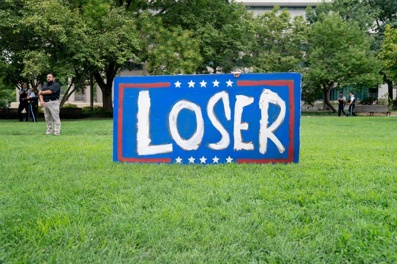 A demonstrator stands next to a sign outside the courthouse.