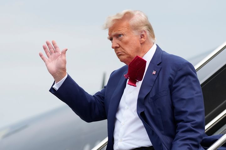 Trump waves as he steps off a plane on his way to Washington to face federal conspiracy charges alleging that he conspired to subvert the 2020 election.