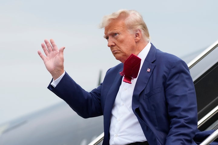 Trump waves as he steps off a plane on his way to Washington to face federal conspiracy charges alleging that he conspired to subvert the 2020 election.