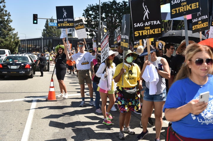 Picketers carry signs on the picket line outside Universal Studios on Friday, Aug. 4, 2023, in Universal City, Calif. The actors strike comes more than two months after screenwriters began striking in their bid to get better pay and working conditions. (Photo by Richard Shotwell/Invision/AP)