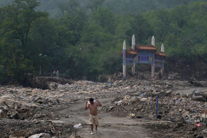 A man walks near a gate way near the flood devastated Nanxinfang village on the outskirts of Beijing, Friday, Aug. 4, 2023. Heavy rain and high water levels on rivers in northeastern China were threatening cities downstream on Friday, prompting the evacuation of thousands, although the country appears to have averted the worst effects of the typhoon season battering parts of east Asia. (AP Photo/Ng Han Guan)