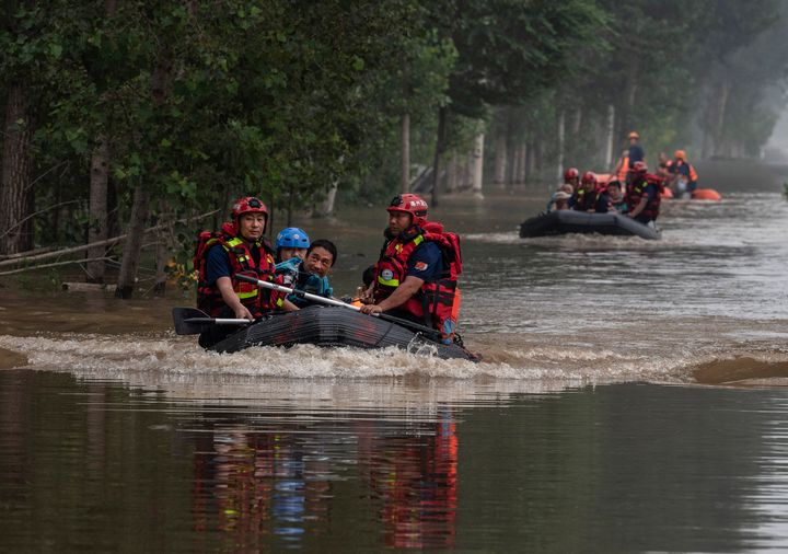 ZHUOZHOU, CHINA - AUGUST 03: Local residents are helped in a boat to safety by rescuers in an area inundated with floodwaters on August 3, 2023 near Zhuozhou, Hebei Province south of Beijing, China. Disaster response teams have been working to control floodwaters and help stranded residents after the strongest storm in years battered northern China. The extreme rainfall from Typhoon Doksuri was the heaviest to hit Beijing in 140 years, inundating the capital and triggering flash floods and landslides. In nearby Hebei province, officials said floodwaters could take a month to recede. More than 100,000 people were evacuated from the hard-hit city of Zhuozhou, where rescuers used rafts to reach people trapped in villages cut off by deep water. (Photo by Kevin Frayer/Getty Images)