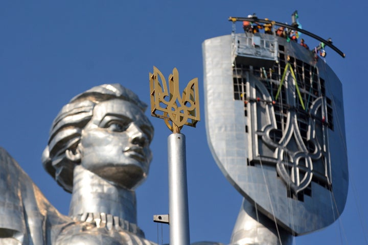 Workers install the trident coat of arms of Ukraine on a shield of the Motherland Monument, now titled "Mother Ukraine." The statue was built in 1981 and originally had the Soviet-era hammer-and-sickle symbol on its shield, before it was replaced as part of a wider effort to reclaim Ukraine's cultural identity from its Communist past.