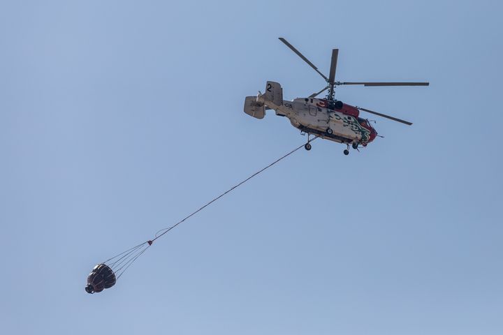 A helicopter of the Jordanian Fire Department is seen over the burnt area, Alassa, Cyprus, on A