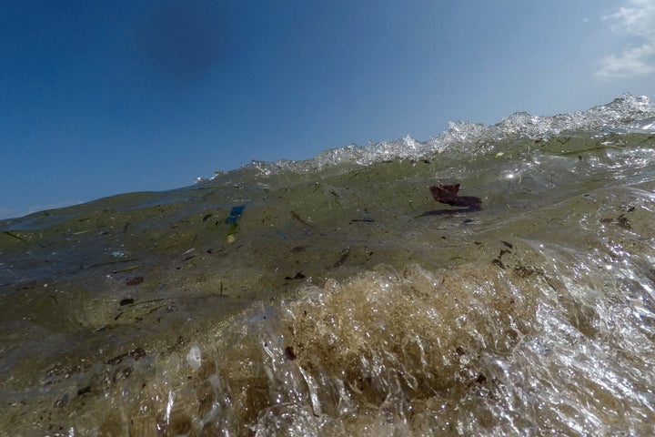 Plastic and trash float in the water on the beach at Portals Nous on Mallorca.