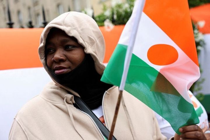 Ένα άτομο κρατάει τη σημαία του Νίγηρα έξω από την πρεσβεία του Νίγηρα για να υποστηρίξει τον πρόεδρο του Νίγηρα Μοχάμεντ Μπαζούμ στο Παρίσι, Γαλλία, 5 Αυγούστου 2023.