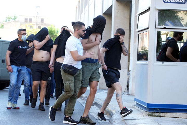 Soccer fans covering their faces, most of them from Croatia, are escorted by police as they leave the Athens Police Headquarters, Greece, Wednesday, Aug. 9, 2023. Ninety-four fans of Croatia's Dinamo Zagreb are appearing in court this morning for a preliminary hearing over Monday night's fan violence that left a fan of Greece's AEK dead and another eight people injured. (AP Photo/Petros Giannakouris)