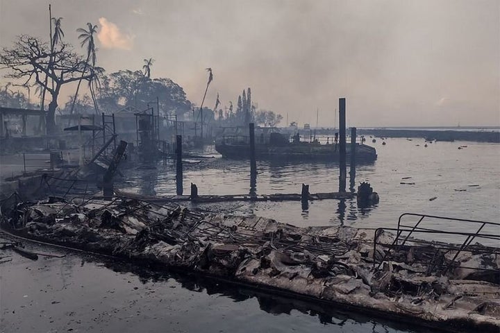 A charred boat lies in the scorched waterfront Wednesday after wildfires fanned by the winds of a distant hurricane devastated Maui's city of Lahaina.