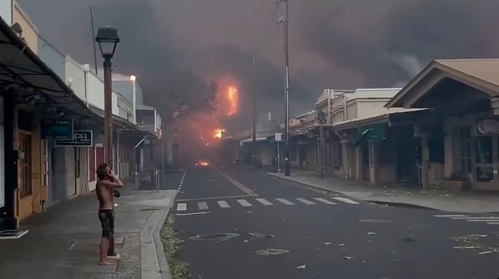 People watch as smoke and flames fill the air from raging wildfires on Front Street in downtown Lahaina, Maui. 