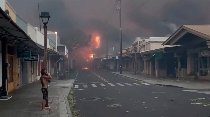 People watch as smoke and flames fill the air from raging wildfires on Front Street in downtown Lahaina, Maui. 