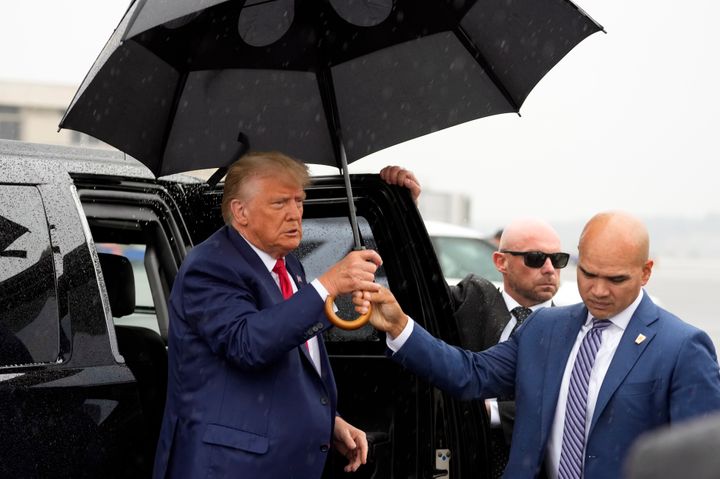 Valet Walt Nauta hands former President Donald Trump an umbrella before he speaks at Ronald Reagan Washington National Airport, Aug. 3, 2023, in Arlington, Va. 