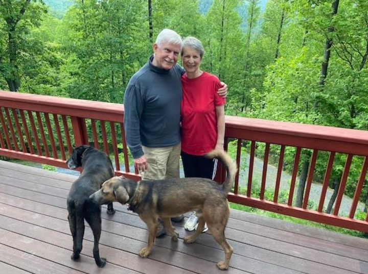 The author and husband Keith with dogs in May 2021 on the deck of their home, Vanaprastha, in the Blue Ridge Mountains of Virginia.