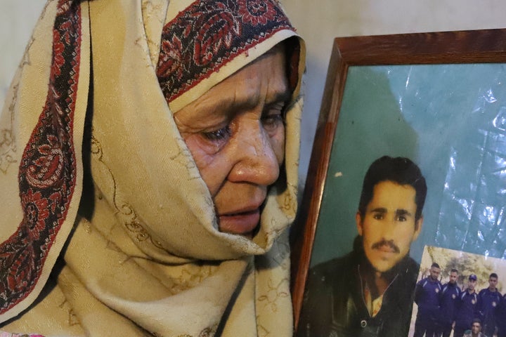 The mother of Mohammed Hassan, a Pakistani porter who died during a summit of K2, weeps while she holds a portrait of him at their home in Tasar, Pakistan.