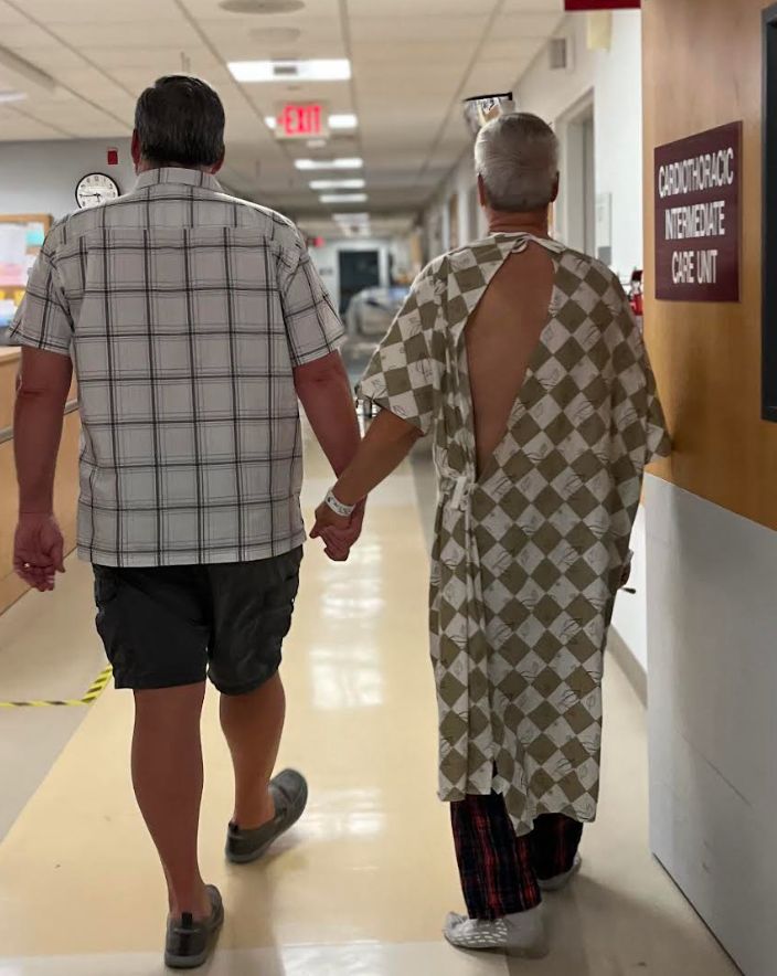 The author (right) and his husband, Paul, walking in the hospital after his bypass surgery.