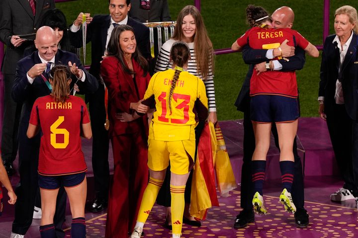 Ο πρόεδρος της ισπανικής ομοσπονδίας ποδοσφαίρου, Λουίς Ρουμπιάλες, δεξιά, αγκαλιάζει την Teresa Abelleira στο βάθρο μετά τη νίκη της Ισπανίας στον τελικό του Παγκοσμίου Κυπέλλου ποδοσφαίρου γυναικών εναντίον της Αγγλίας στο Stadium Australia στο Σίδνεϊ της Αυστραλίας, Κυριακή, 20 Αυγούστου 2023. Στην φωτογραφία από αριστερά, είναι ο πρόεδρος της FIFA Gianni Infantino με την Aitana Bonmati, η βασίλισσα Letizia της Ισπανίας με την αναπληρωματική τερματοφύλακα Enith Salon ενώ παρακολουθεί η πριγκίπισα Σοφία. (AP Photo/Mark Baker)