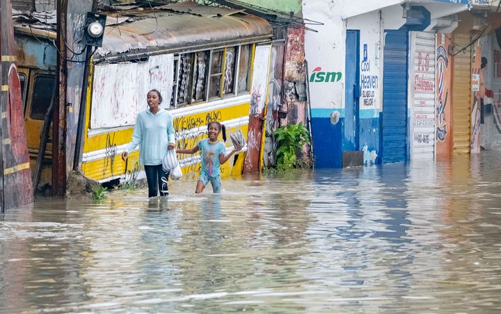 People walk through a street flooded by the rains of Tropical Storm Franklin in Santo Domingo, Dominican Republic, on Aug. 22, 2023. 
