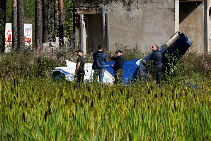 Russian servicemen inspect a part of a crashed private jet near the village of Kuzhenkino, Tver region, Russia, Thursday, Aug. 24, 2023. Russian mercenary leader Yevgeny Prigozhin, the founder of the Wagner Group, reportedly died when a private jet he was said to be on crashed on Aug. 23, 2023, killing all 10 people on board. (AP Photo/Alexander Zemlianichenko)