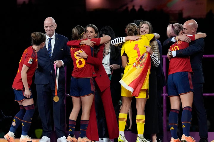 From left, FIFA President Gianni Infantino, Queen Letizia, Spain's Princess Infanta Sofia President of Spain's soccer federation, Luis Rubiales, hug Spain's players the podium following Spain's win in the final of Women's World Cup soccer against England at Stadium Australia in Sydney, Australia, Sunday, Aug. 20, 2023. (AP Photo/Alessandra Tarantino)