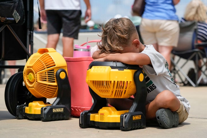 FILE - Braxton Hicks, 7, of Livingston, Texas, holds his face to a portable fan to cool off during the DYB, formerly Dixie Youth Baseball, Little League tournament in Ruston, La., Wednesday, Aug. 9, 2023. Another record-setting day of high temperatures is forecast in the Dallas/Fort Worth area Saturday, Aug. 26, 2023, before a slight cooling trend moves into the area, according to the National Weather Service as heat warnings stretch from the Gulf Coast to the Southeastern U.S. and upper Mid-South. (AP Photo/Gerald Herbert, File)