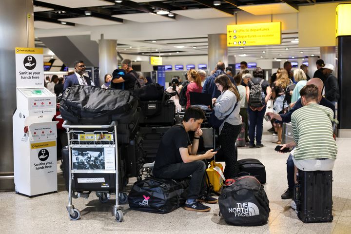 Travellers wait near the British Airways check-in area at Heathrow Airport, as Britain's National Air Traffic Service restricts UK air traffic due to a technical issue causing delays.