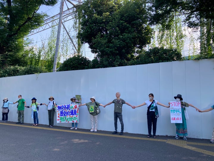 6月に開かれたヒューマンチェーン（人間の鎖）のデモで、工事用の白い壁で覆われている神宮第二球場を手を繋いで囲み、再開発の見直しを訴える人々（20023年6月25日）