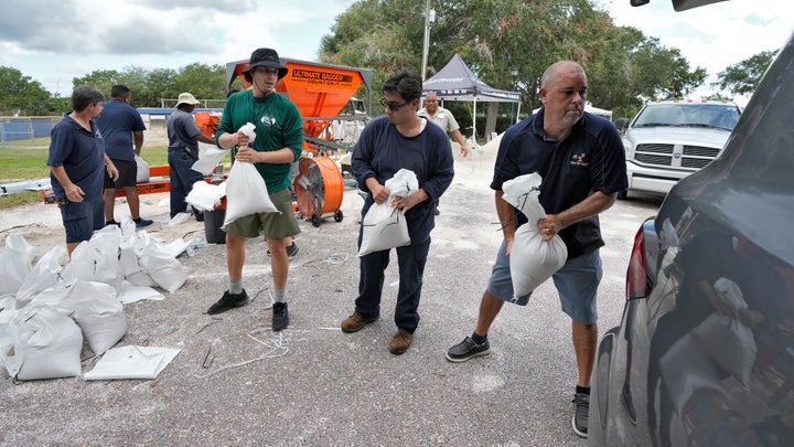 Members of the Tampa Parks and Recreation Department help residents load sandbags Monday in Tampa.