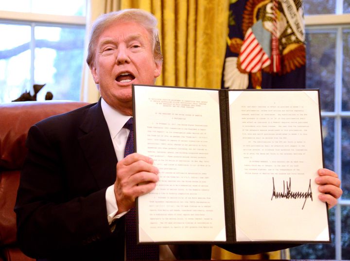 Then-President Donald Trump holds up an executive order levying tariffs on solar panel and washing machine imports from China and other countries in January 2018.