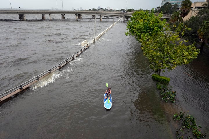 Flood waters pushed by Hurricane Idalia pour over the sea wall along Old Tampa Bay as paddleboarder Zeke Pierce, of Tampa, rides on Aug. 30 in Tampa, Florida.