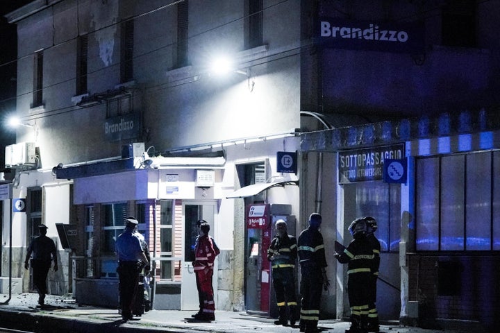 Firefighters and gendarmes stand at Brandizo train station where five railway workers died after being hit by a train during overnight maintenance work.